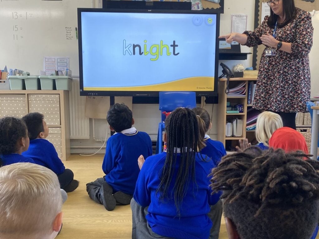 Children in a Welsh primary school on the carpet during a phonics lesson, with the word knight on the screen